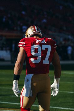 a football player is standing on the field with his hands in his pockets and looking down