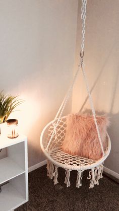 a hammock hanging from the ceiling in a room next to a table with a potted plant on it