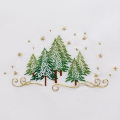 embroidered christmas trees on white fabric with gold stars and snowflakes in the background