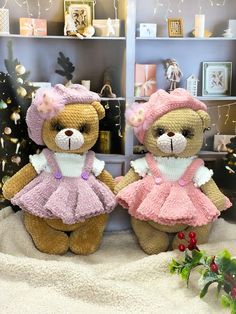 two teddy bears dressed in pink and white are sitting next to each other near a christmas tree