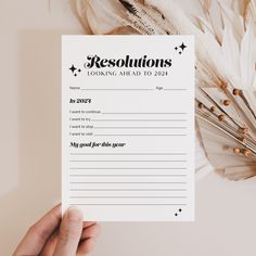 a person holding up a paper with the words resolutions on it and some feathers