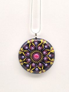 a purple and yellow necklace with a flower design on it