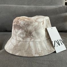 a white hat sitting on top of a gray couch next to a tag that says zap