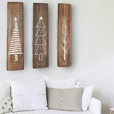 three wooden christmas trees are hanging on the wall above a white couch in a living room