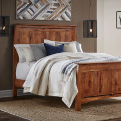 a wooden bed frame in a bedroom with pillows and blankets on top of the bed