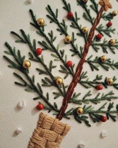 a hand embroidered christmas tree with gold bells on it's needles and red berries