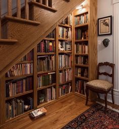 a bookcase with many books in it next to a stair case