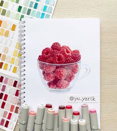 a drawing of raspberries in a glass bowl with crayons next to it