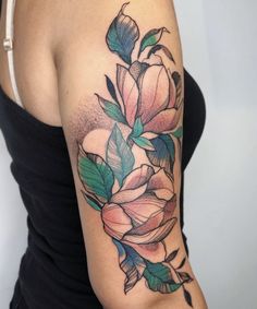 a woman wearing a black tank top with flowers on her arm and shoulder tattoo design