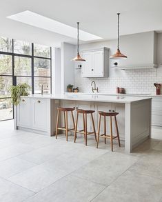 a kitchen with two stools next to an island in front of a large window