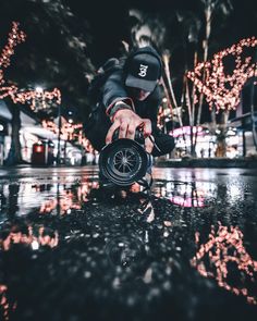 a man kneeling down on the ground with a toy in his hand and lights behind him