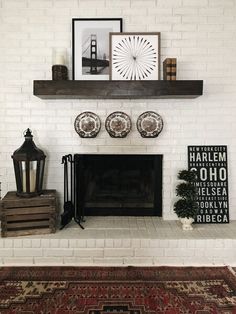 a white brick fireplace with black and white plates on the mantel above it in a living room