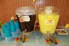 winnie the pooh themed birthday party with cups and desserts on a blue table cloth