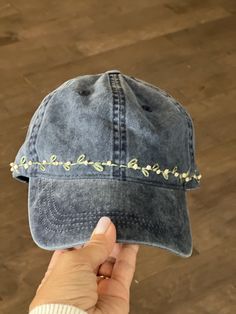 someone is holding up a denim hat with embroidered words on it, and the cap has been