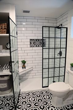 a bathroom with black and white tiles on the floor, shower stall, toilet and shelving unit