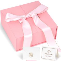 a pink gift box with a white ribbon and a thank you card in front of it