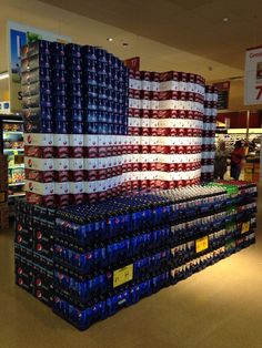 several stacks of soda cans stacked on top of each other in a grocery store with the american flag painted on them