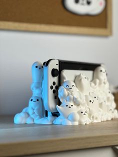 a nintendo wii game controller sitting on top of a wooden table next to ghost figurines