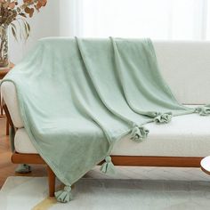 a living room with a white couch covered in a light green blanket