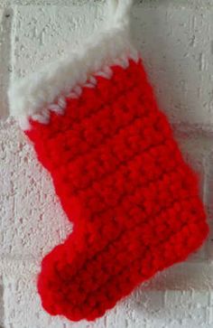 a red and white knitted stocking hanging on a brick wall