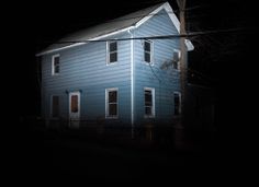 a blue house is lit up at night with the light on it's windows