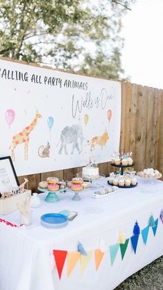 a table topped with cupcakes and cakes next to a sign that says falling all over animals