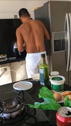 a shirtless man in the kitchen preparing food