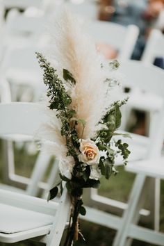 a bouquet of flowers sitting on top of a white folding chair next to a row of chairs