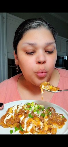 a woman eating food from a white plate