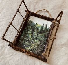 an old photo frame is sitting on a white sheet with some branches hanging from it