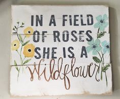 a sign that says in a field of roses she is a wildflower on it