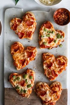 heart shaped pizzas on a cutting board with toppings