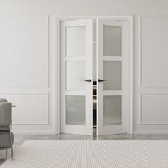 an empty white room with two chairs and a large glass door leading to another room