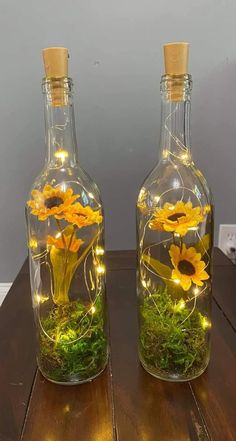 two glass bottles with flowers in them sitting on a table