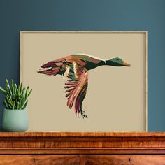 a painting of a duck flying over a wooden dresser next to a potted plant