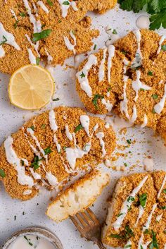 some food is laying out on a white surface with a fork and lemon wedges next to it