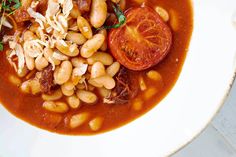 a white bowl filled with beans and tomatoes