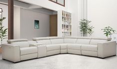 a large white sectional sofa sitting in a living room next to a tall planter