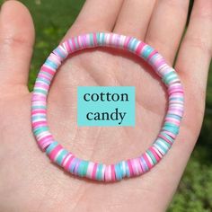 a person holding a colorful bracelet with cotton candy on it's end and the words cotton candy written in blue