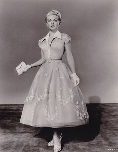 a black and white photo of a woman wearing a dress with flowers on the skirt