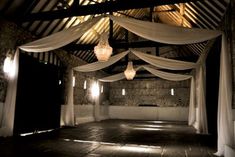 an indoor wedding venue with white drapes and chandeliers