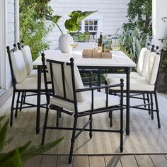 an outdoor dining table and chairs with white cushions