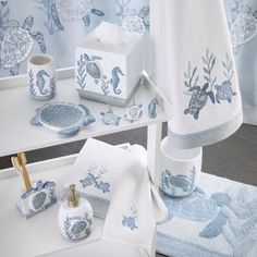 the bathroom is decorated with blue and white sea life towels, soap dispenser, toothbrush holder, toilet paper roll, and other items