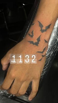 a person's hand with a tattoo on it that has bats all over it