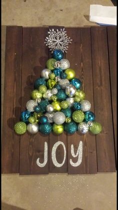 a christmas tree made out of ornaments and the word joy written on it in white paint