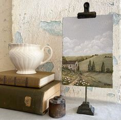 there is a white vase sitting on top of two books next to an easel