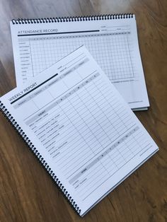 two notebooks sitting next to each other on top of a wooden table with papers