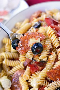 a pasta salad with olives, tomatoes and meat