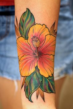 a woman's arm with a colorful flower tattoo on the left side of her arm