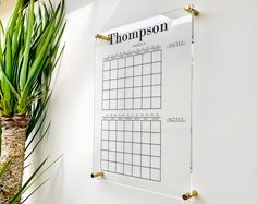 a white wall with a calendar on it next to a potted plant and other plants